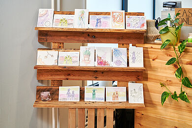 Bunte Postkarten auf einem Holzregal in der Elsterkammer