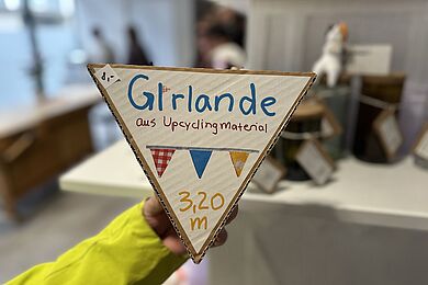 eine Hand hält eine Girlande aus Upcyclingmaterial hoch