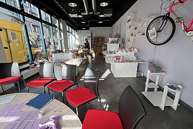 Blick in den Raum, Warenauslage und eine Sitzecke im Vordergrund
