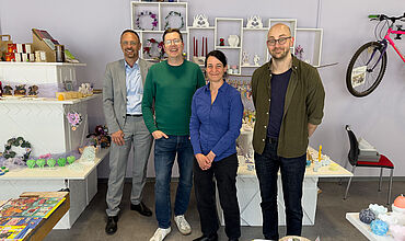 Gruppenfoto im Ladengeschäft Elsterkammer, v.l. Tobias Schmidt in einem hellgrauen Anzug, Martin Meißner in Jeans und einem grünen Pullover, Christin Melcher in einer blauen Bluse und schwarzer Hose und Dr. Frank Braun in einer dunklen Hose und einem grünen Hemd.
