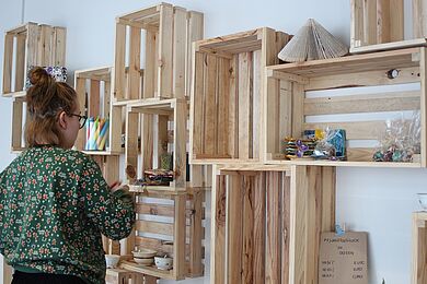 Eine Mitarbeiterin räumt Waren in das Regal der Elsterkammer