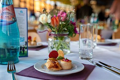 Eingedeckter Tisch mit Blätterteighäppchen und Blumen im Hintergrund