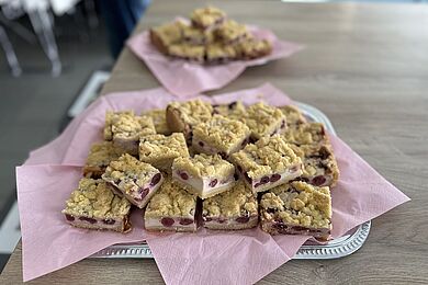 Stücke eines Blechkuchens - Kirsch-Quark mit Streuseln auf einem Servierblech mit einer rosafarbenen Serviette