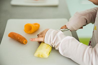 Ein Kind schneidet Gemüse in der Kinderwohngruppe