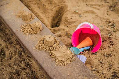 Sandkasten mit Sandspielzeug und Sandkuchen