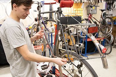Ein Jugendlicher montiert ein Hinterrad