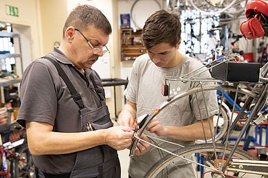 Fachanleiter und Jugendlicher besprechen eine Reparatur am Fahrrad