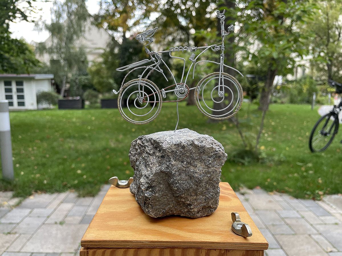 Pokal der Sternfahrt: Auf einem Holzbrett befindet sich ein Stein, auf dem ein Fahrrad aus Draht angebracht wurde