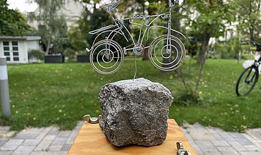 Pokal der Sternfahrt: Auf einem Holzbrett befindet sich ein Stein, auf dem ein Fahrrad aus Draht angebracht wurde