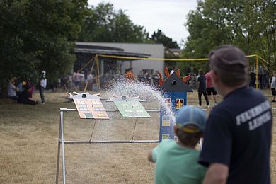 Junge und Feuerwehrmann mit dem Wasserspritzschlauch