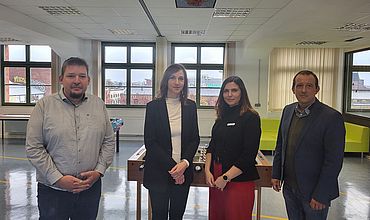 Vier Personen stehen nebeneiander in einem Schulpausenraum. Bei den zwei Männern und zwei Frauen handelt es sich um die Bereichs- und Abteilungsleitung Wolfgang-Mutzeck-Schule und die Bürgermeisterin Vicki Felthaus und Amtsleiter Dr. Nicolas Tsapos