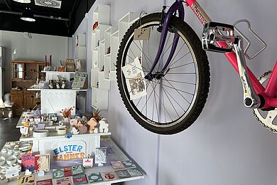 rechts ein Fahrrad an der Wand, Warenauslagen im Hintergrund