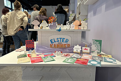 Auslage von Postkarten, im Hintergrund Menschen