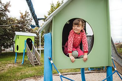 Ein Mädchen spielt auf dem Klettergerüst der Kinderwohngruppe