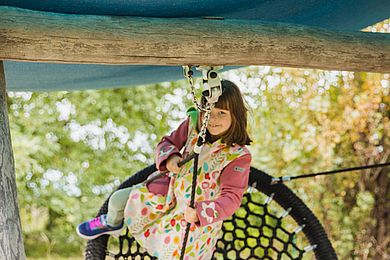 Ein Mädchen schaukelt im Garten der Kinderwohngruppe